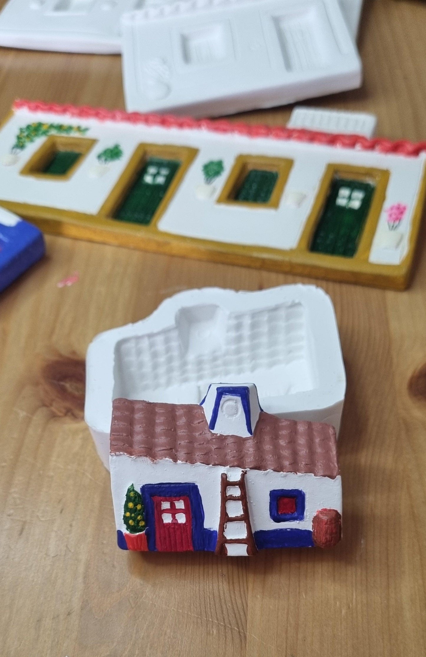 Molde de casinha pequena com peça colorida no interior: telhado castanho e portas azuis