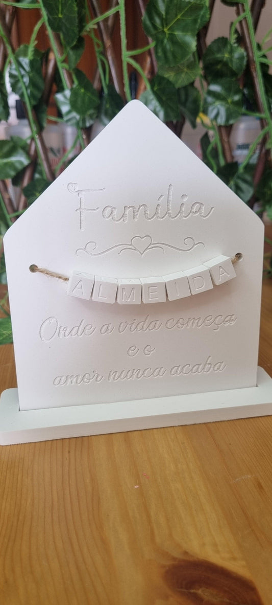 Molde decorativo em forma de casa branca com “Família” e detalhe com corações