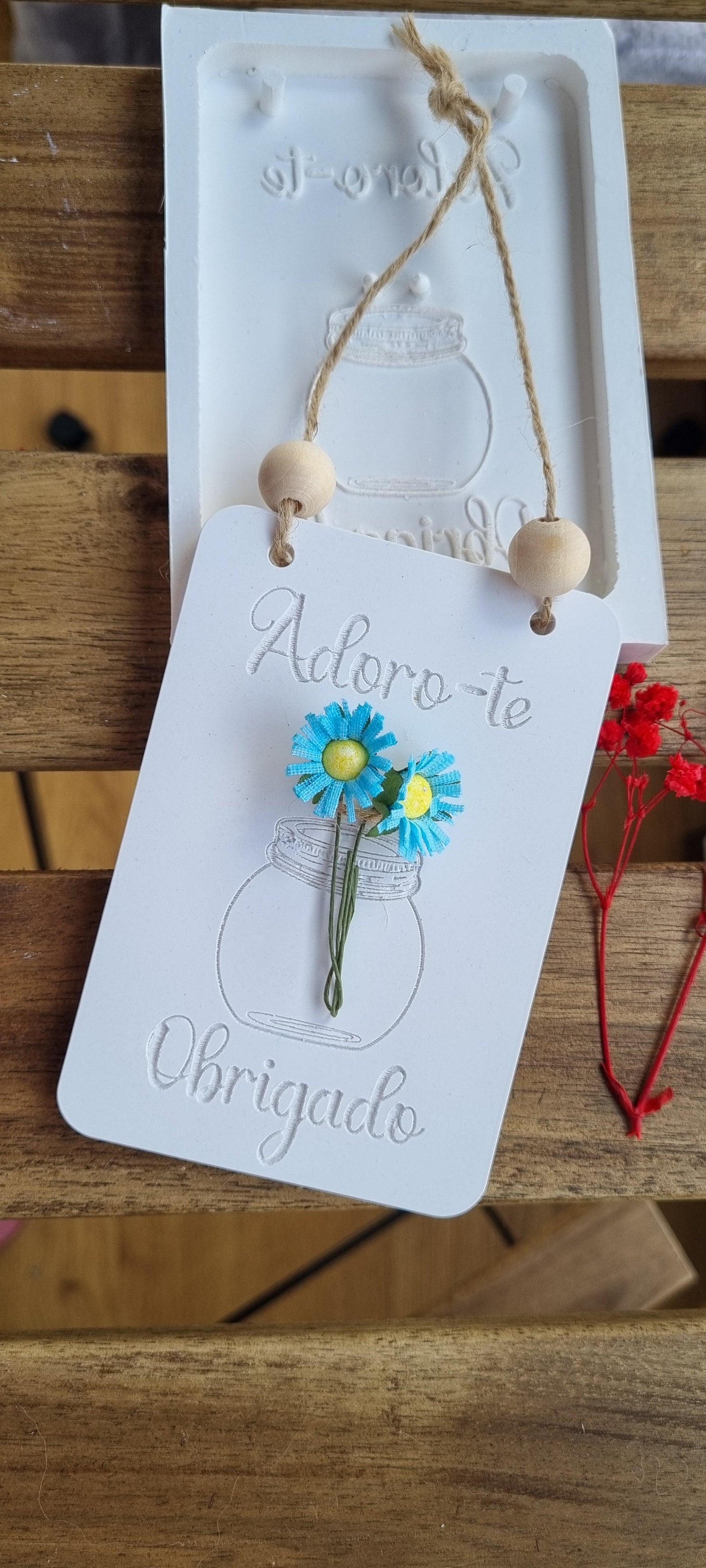 Molde de cartão branco com vaso desenhado, flores azuis e cordão com contas