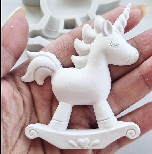 Molde de unicórnio branco 2D com chifre e base ondulada, segurado na mão