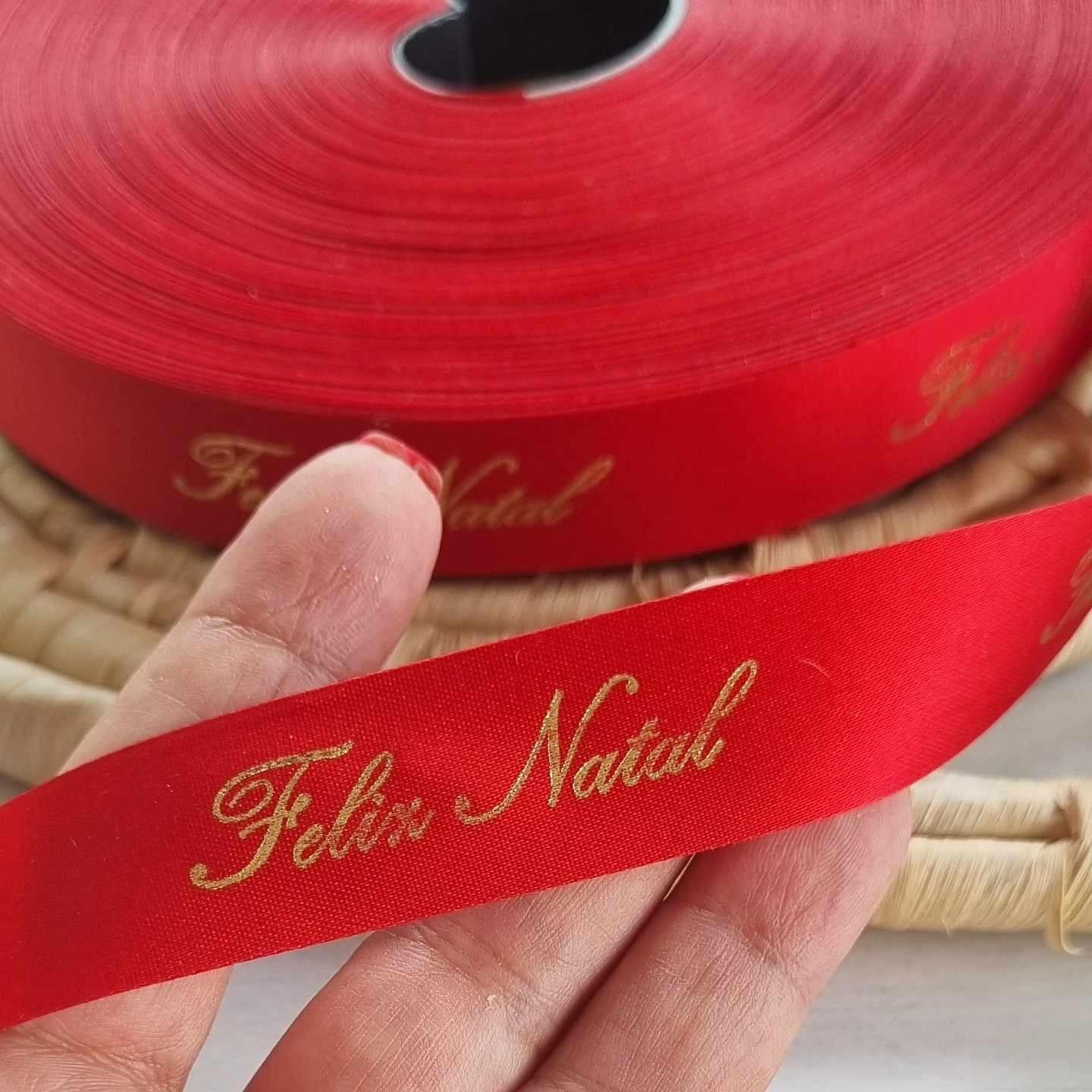 Fita vermelha com texto dourado “Feliz Natal” em close-up