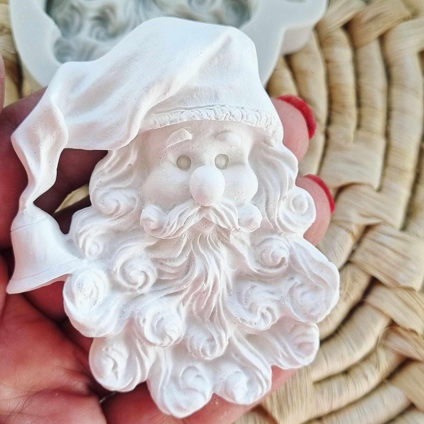 Moldes de cabeça do Pai Natal em relevo branco, rosto e barba visíveis, segurado na mão