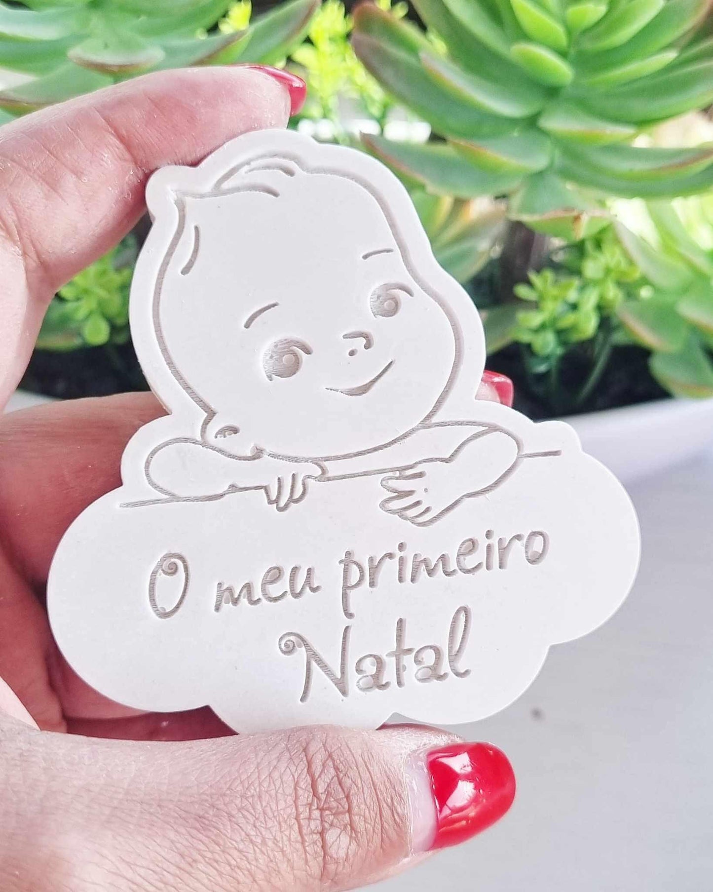 Molde branco em formato de bebé sorridente com a inscrição “O meu primeiro Natal”