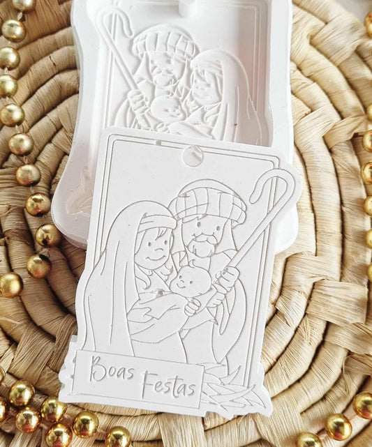 Molde de presépio branco em relevo com furo, figuras e inscrição 'Boas Festas'.