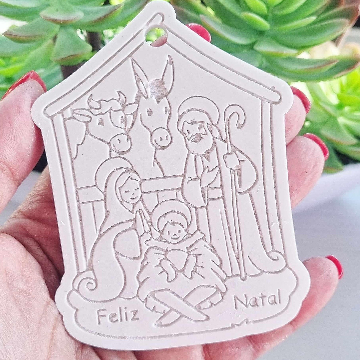 Molde branco de presépio com furo, relevo de figuras e “Feliz Natal”