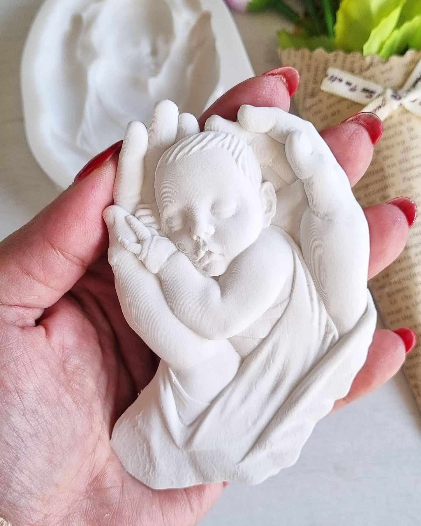 Molde de mãos com bebé em relevo, branco, nas mãos de adulto, detalhe do bebé