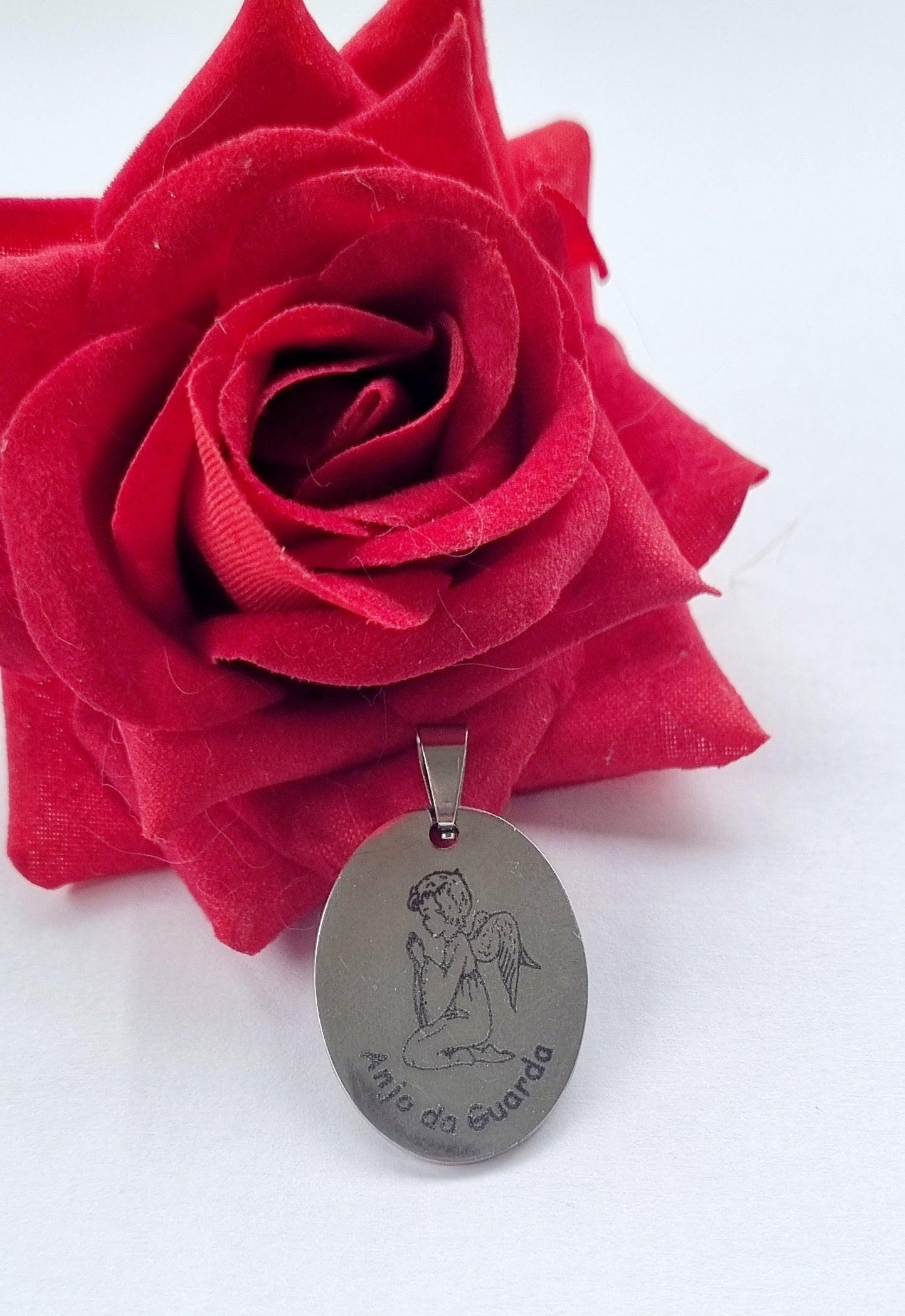 Medalha oval prateada com figura de anjo da guarda e argola superior