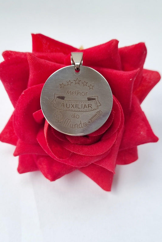 Medalha prateada circular com argola e gravação 'Auxiliar do mundo'