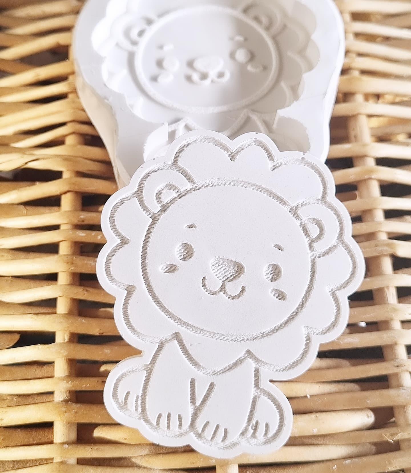 Molde decorativo branco em forma de leão, com contorno e rosto bordado