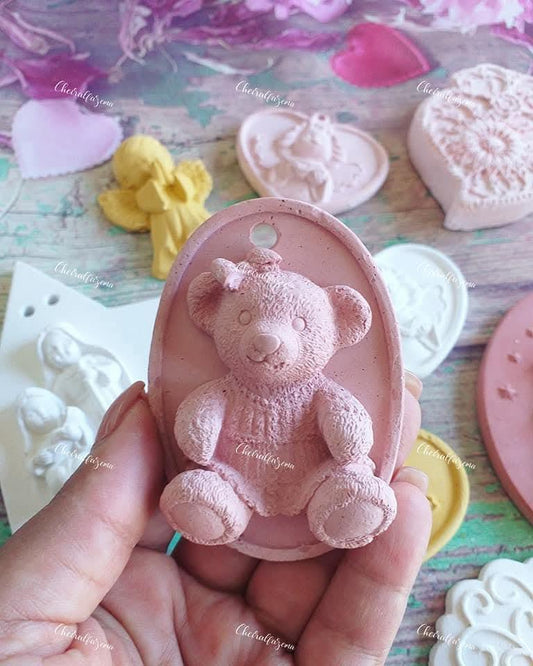 Gesso cor-de-rosa em forma de urso em baixo-relevo, oval, segurado na mão