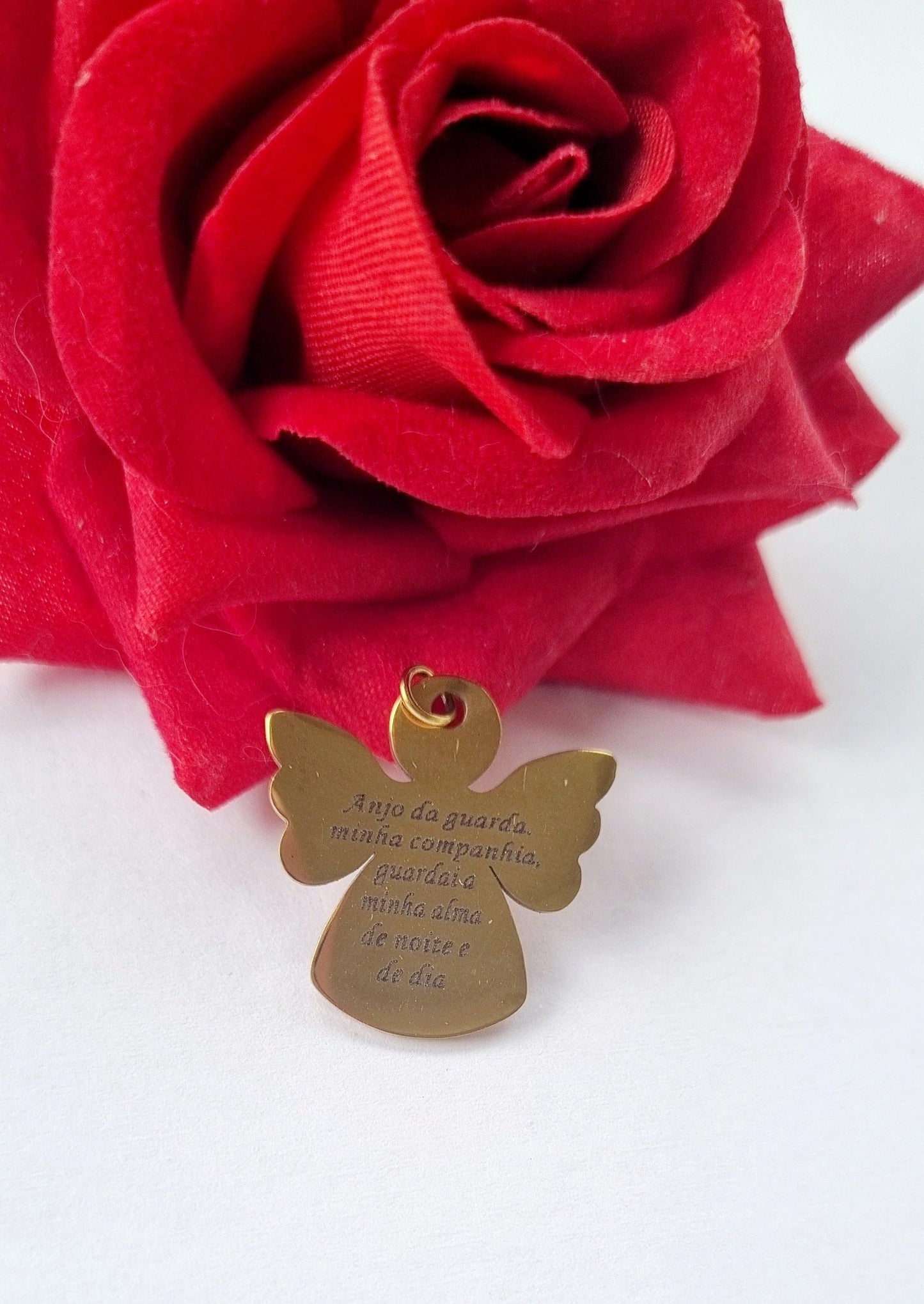 Medalha dourada em forma de anjo, com asas e argola, inscrição no peito.