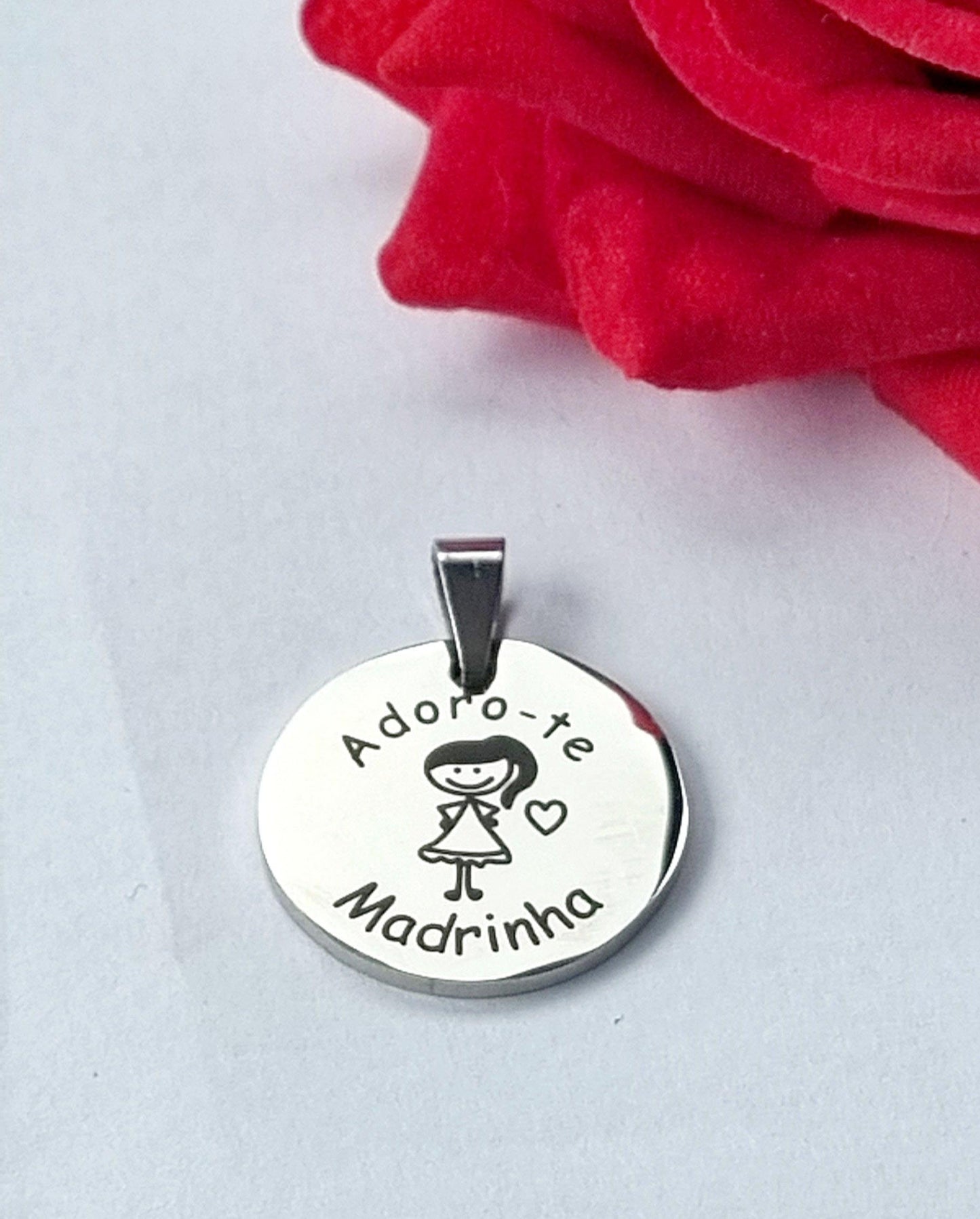 Medalha prateada circular com gravação «Adoro-te Madrinha» e ilustração de menina com coração