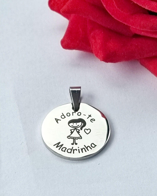 Medalha prateada circular com gravação «Adoro-te Madrinha» e ilustração de menina com coração