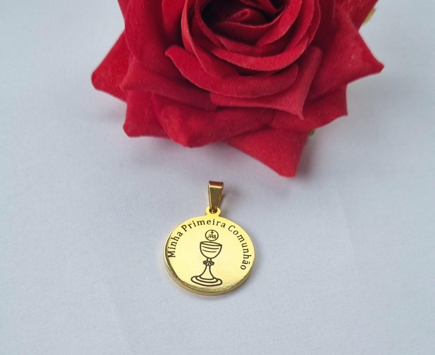 Medalha dourada redonda com cálice e texto «Minha Primeira Comunhão»
