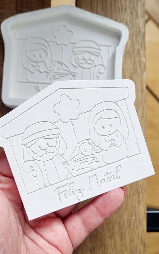 Molde branco de presépio em cabana, com figuras em relevo e “Feliz Natal”