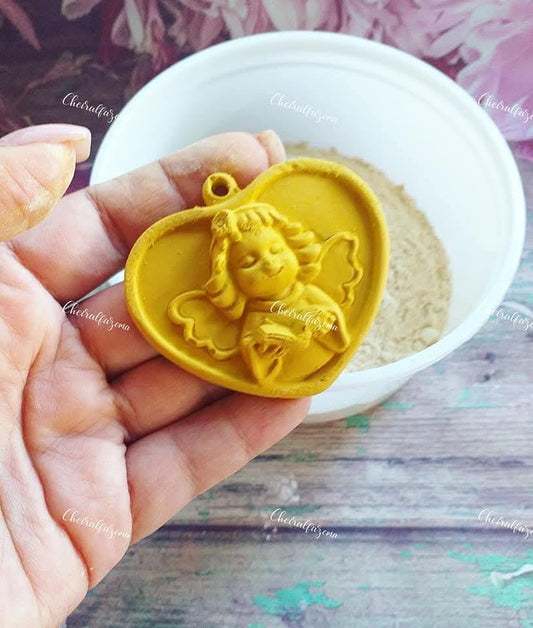 Medalhão de gesso amarelo com relevo de anjo, segurado na mão
