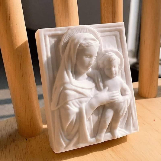Molde branco com relevo da mãe e do bebé ao colo, em detalhe
