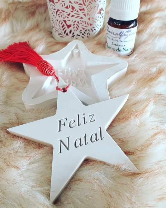 Molde em forma de estrela branca com texto “Feliz Natal” e presilha vermelha