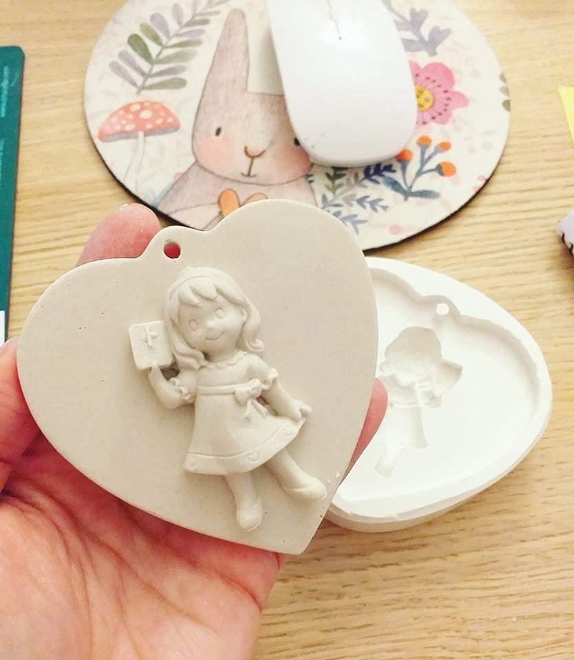 Molde em coração com relevo de menina em vestido, a segurar um livro