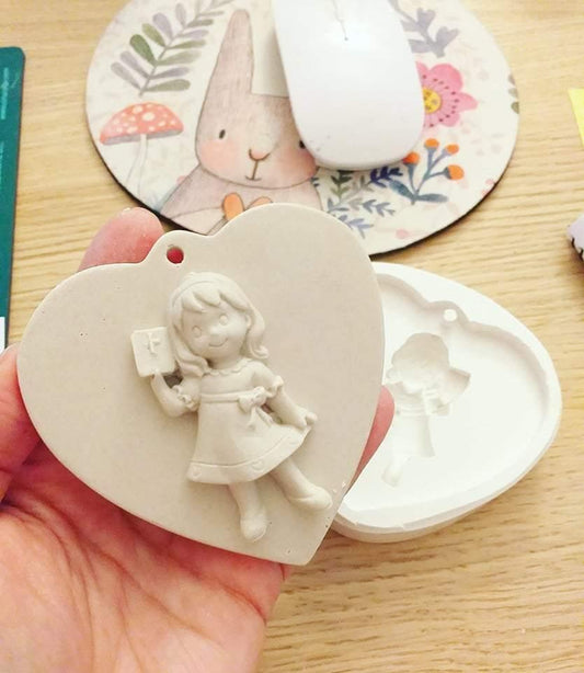 Molde em coração com relevo de menina em vestido, a segurar um livro