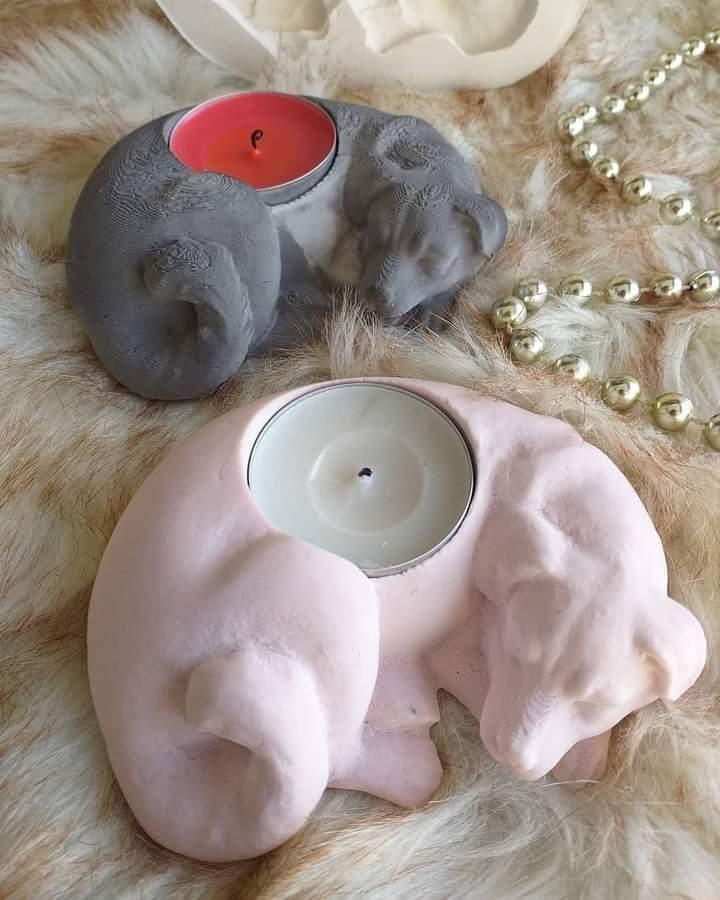 Cão cinzento com vela vermelha e cão branco com vela clara, ambos porta-velas