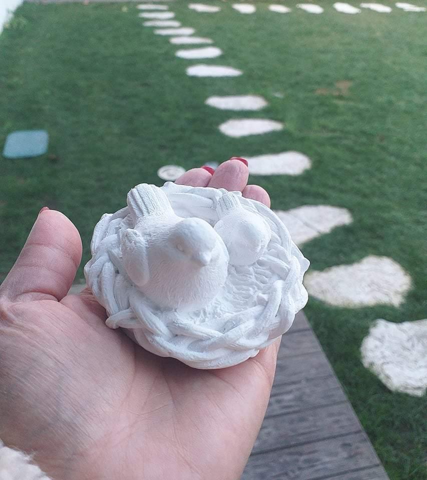 Molde de ninho com passarinhos branco, com pequenos pássaros e bico rosa, na mão