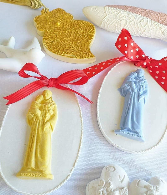 Moldes ovais com figuras de Santo António em relevo dourado e azul, laços vermelhos