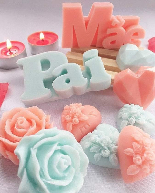 Molde de letras “Mãe” rosa sobre base de madeira, rodeado de sabonetes