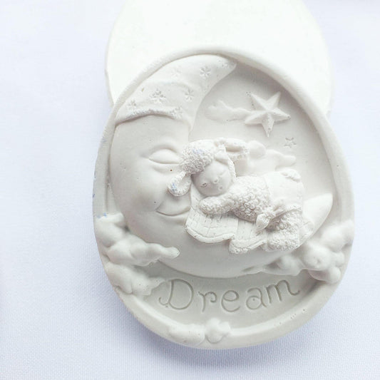 Molde oval branco com relevo de bebé anjo e estrela, inscrição “Dream”.