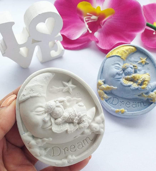 Molde oval branco com relevo de bebé anjo a dormir e estrela, inscrição “Dream”.