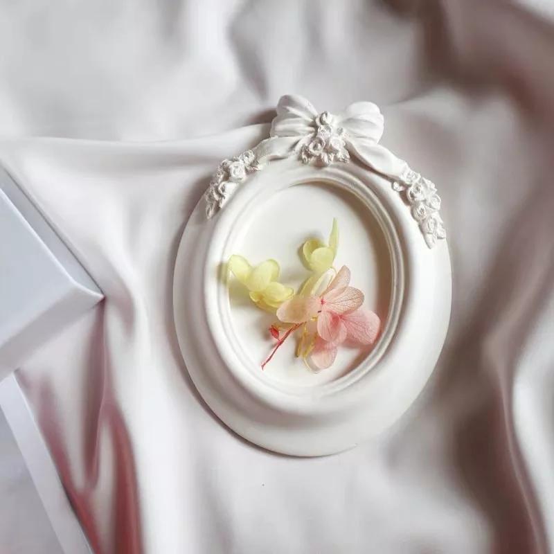 Molde de moldura oval branca com laço, com flores e folhas aplicadas