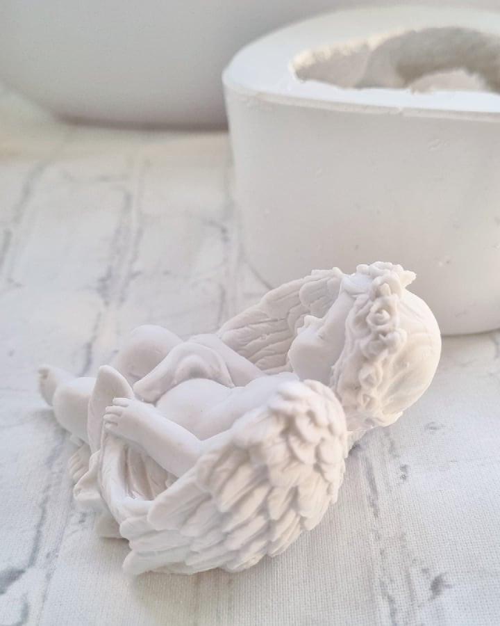 Figura de anjo em relevo com asas detalhadas e decoração floral nas bordas