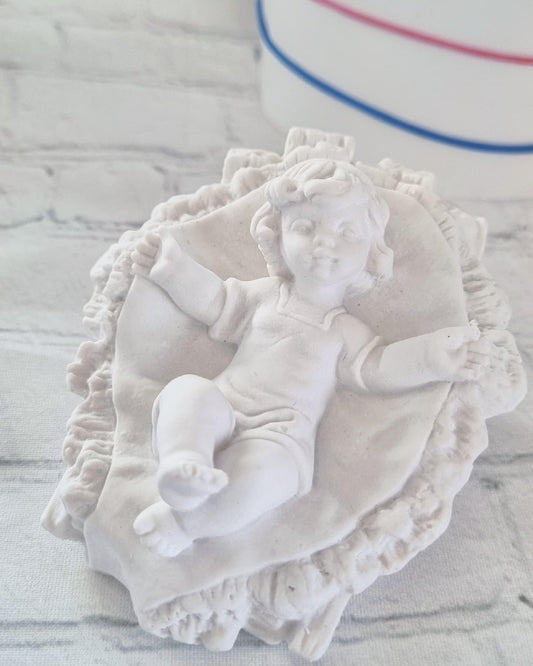 Molde grande do menino Jesus deitado sobre palhas, com auréola esculpida e manto