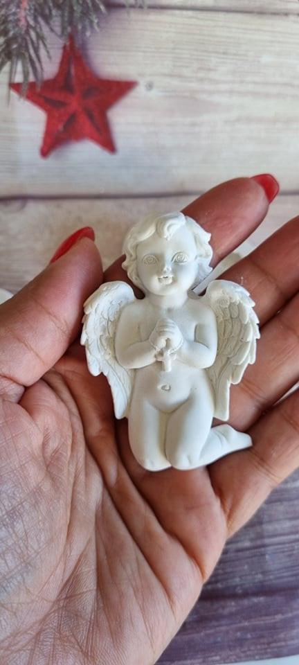 Anjo pequeno de resina branca com rosário, asas e auréola, segurado na mão