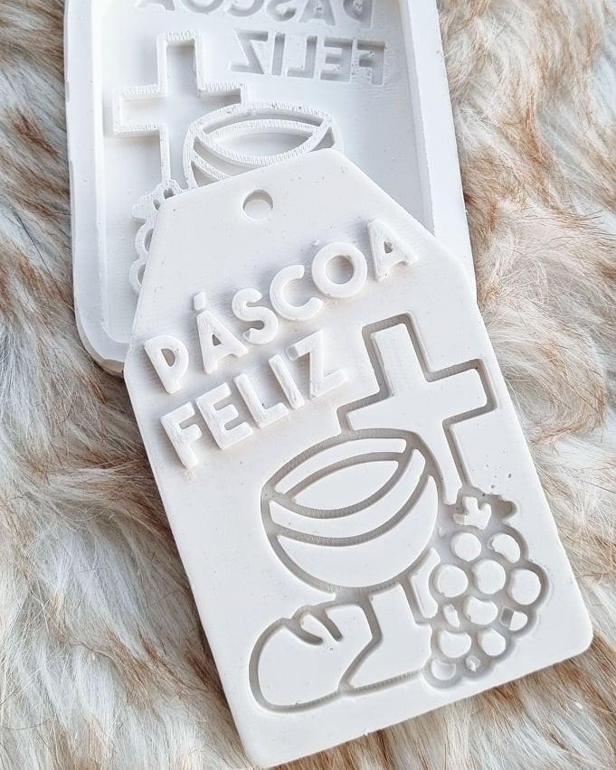 Forma de Páscoa em plástico branco com letras «Feliz Páscoa» e símbolos.