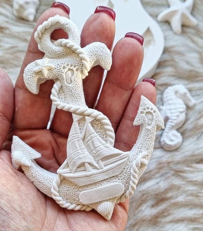 Molde de âncora branco com detalhes em relevo, segurado na mão