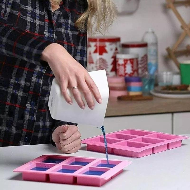 Molde rosa de silicone com 6 cavidades retangulares em uso, a verter líquido