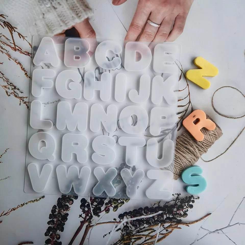 Molde de letras em silicone branco, com letras A-Z e peças coloridas soltas ao redor