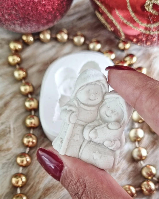 Molde de silicone branco com figuras do presépio, com uma mão a pressionar