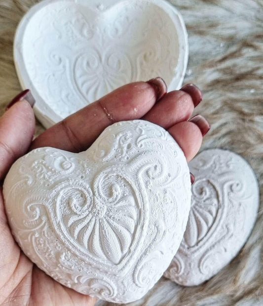 Molde de coração branco em relevo com cornucópias, segurado na mão