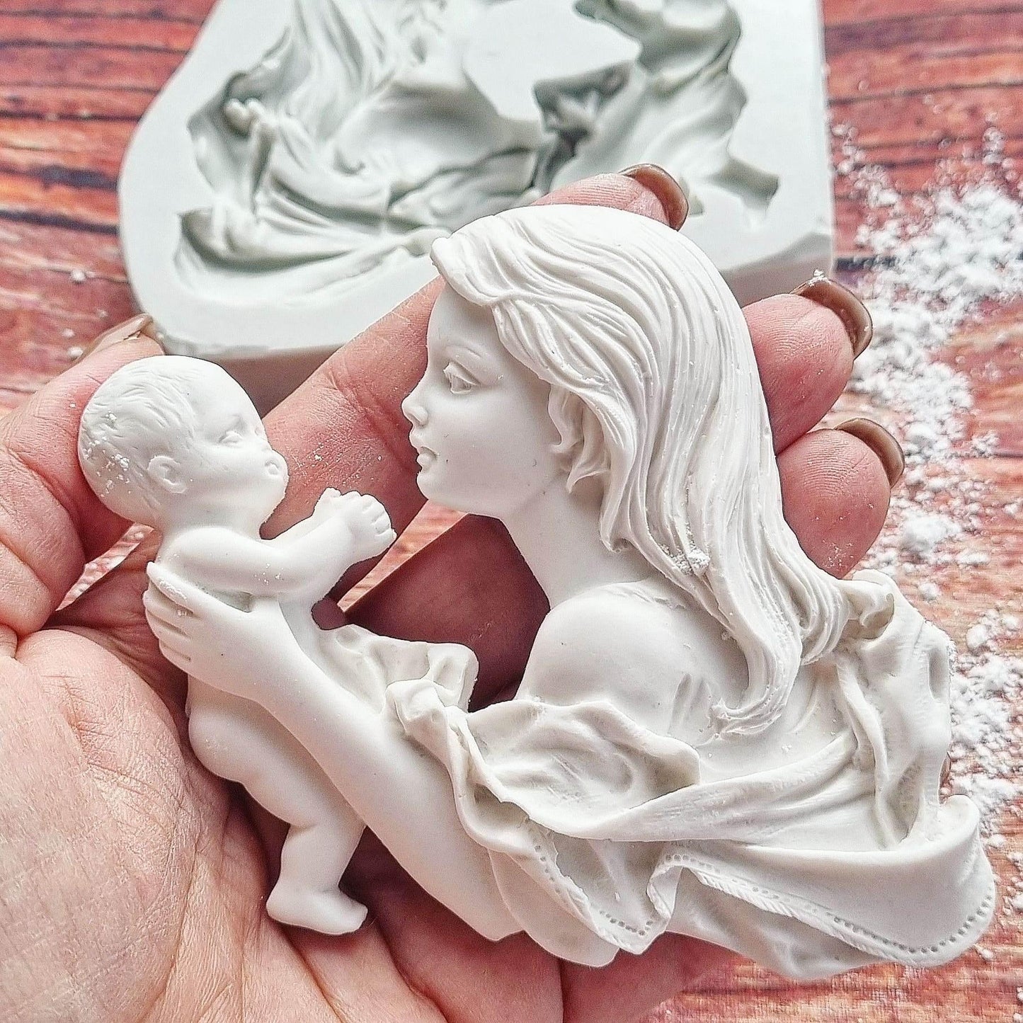 Figura branca de mãe com bebé ao colo, vista lateral em relevo