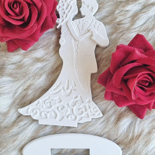 Molde de noivos branco com base e recorte oval; figuras de perfil em relevo
