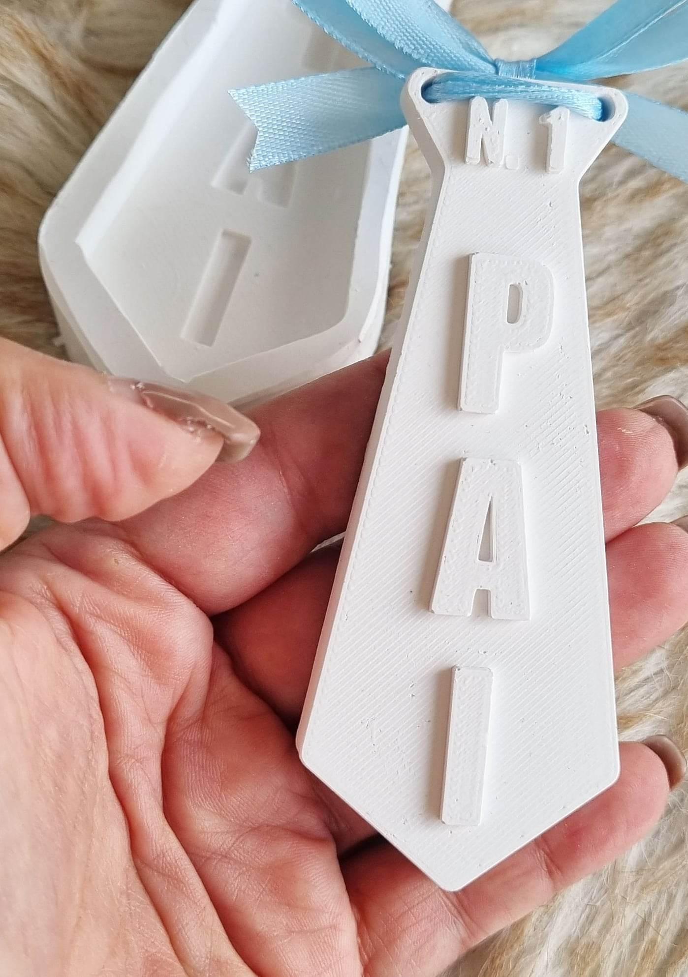 Molde de gravata branco com letras 'PAI' e laço azul para pendurar.