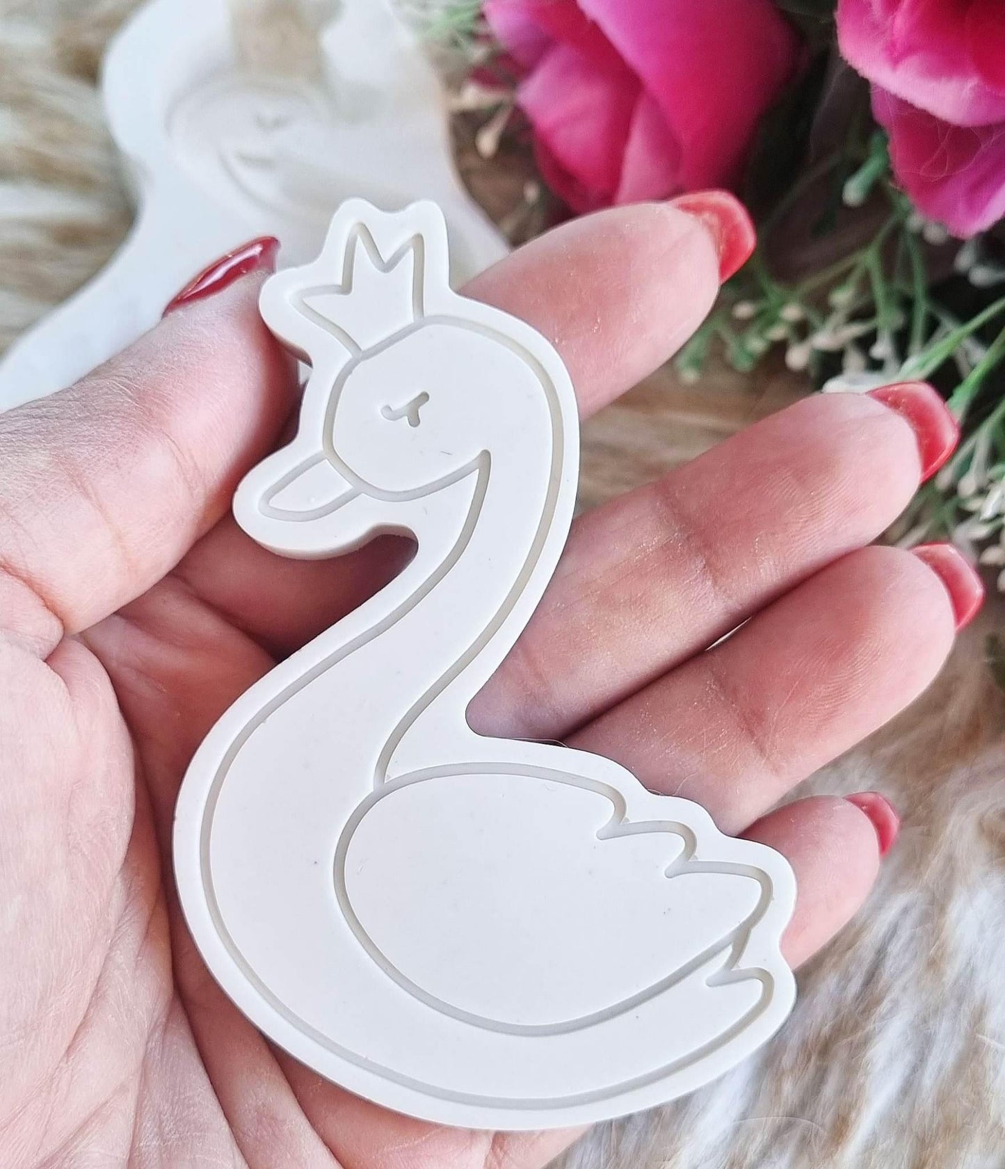 Molde de cisne branco com coroa, visto em detalhe na mão