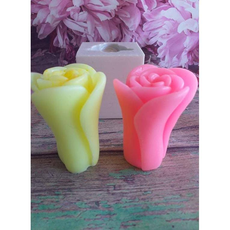 Velas em forma de rosa alta: uma rosa e outra amarela, ao lado de caixa branca