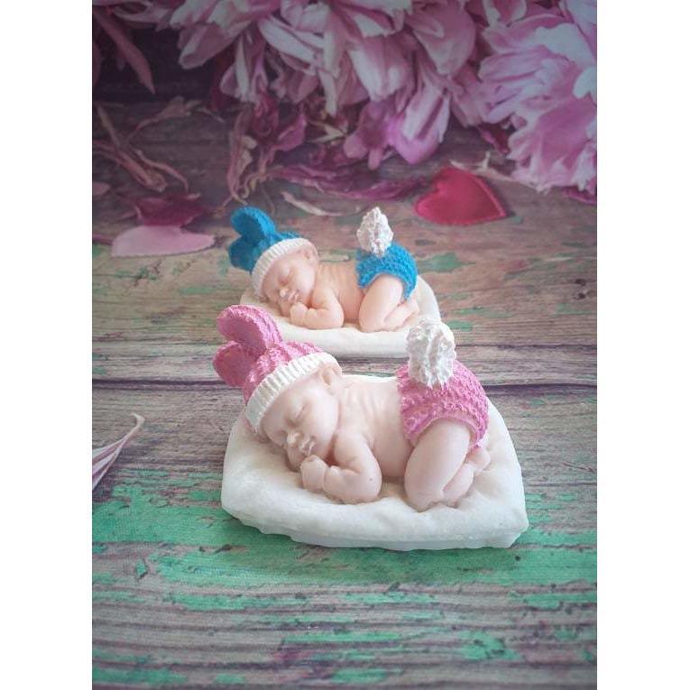 Bebé deitado na almofada branca, com chapéu azul e rosa e meias