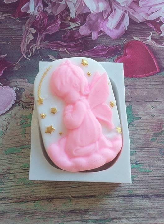 Vela de cera rosa em forma de anjinho menina, com estrelas douradas
