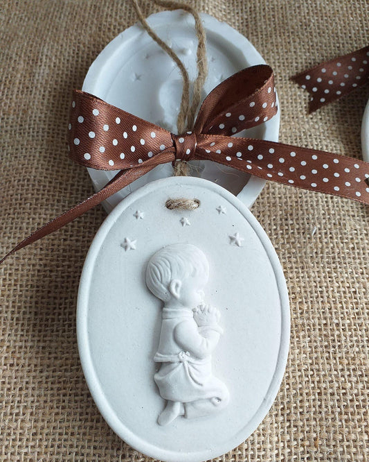 Molde oval branco com menino em relevo e estrelas; fita castanha com bolinhas