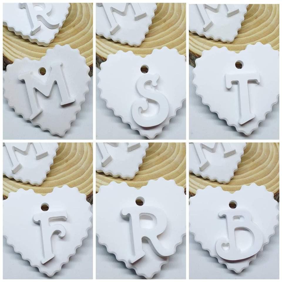 Molde em forma de coração com monogramas em relevo e furo central