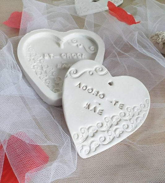 Molde de coração branco com gravação “TE AMO” e relevo decorativo.